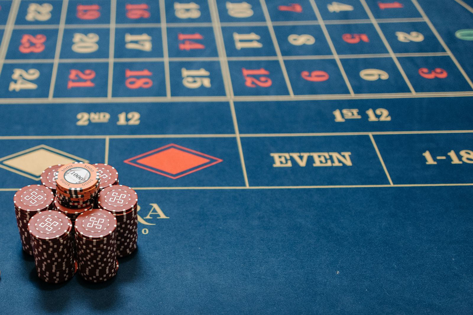 Meja permainan casino dengan tumpukan chip merah